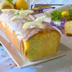 Un delizioso plumcake al limone glassato, decorato con fette di limone e menta, pronto per essere gustato.