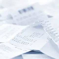 Stos papierowych paragonów, każdy z nich to faktura do paragonu, dokumentująca zakupy.
