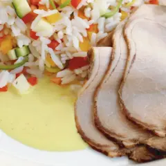 Skivor av saftig benfri kotlett serveras med ris blandat med grönsaker och en krämig sås. Ett perfekt benfri kotlett recept för en god middag.