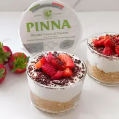 Delizioso dolce al bicchiere con ricotta fresca, fragole e scaglie di cioccolato. Perfetto per un dessert leggero e gustoso.