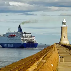 Duży prom DFDS Seaways wypływa z portu, kierując się na Bornholm. Obok stoi latarnia morska.