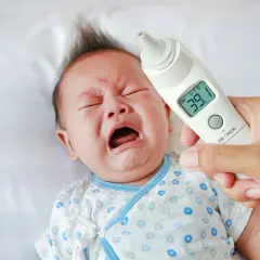 Płacz dziecka i termometr wskazujący 39.1°C. Ewidentna gorączka u dziecka, które nie chce dać się zbadać.