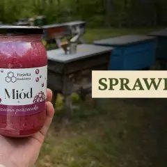 Słoik miodu z czarną porzeczką, na tle pasieki. Czy miód akacjowy się krystalizuje? Sprawdź!