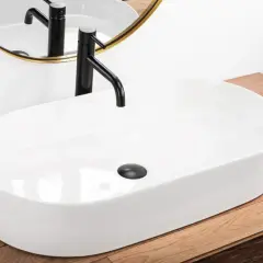 Elegancki zlew nablatowy łazienka z czarną baterią i złotym lustrem.
