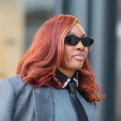 Feuerrote Haare, auffällige Sonnenbrille und ein Blazer – diese Frau verkörpert den Trend für Frisuren 2026.