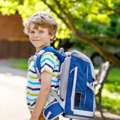 Niño sonriente con mochila azul, listo para ir al cole.