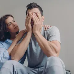 Donna consola un uomo disperato, con le mani sul viso. Forse lui non si fida di me senza motivo, ma lei cerca di rassicurarlo.