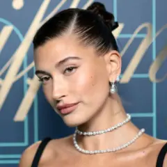 Elegancka kobieta z gładkim kokiem, w perłowej biżuterii, prezentuje klasyczny styl.