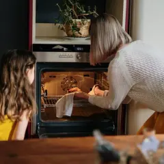 Mama i córka wkładają ciasto do rozgrzanego piekarnika. To ich pierwsze uruchomienie piekarnika po przeprowadzce.
