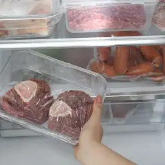 Main du réfrigérateur, deux morceaux de viande rouge avec os, emballés dans du film plastique. Viande cuite hors frigo 12h, risque de détérioration.