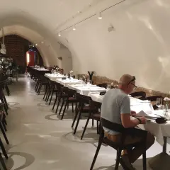 Elegancka sala restauracyjna z białymi obrusami i nakrytymi stołami. W tle bar. To może być najstarsza restauracja w Polsce.