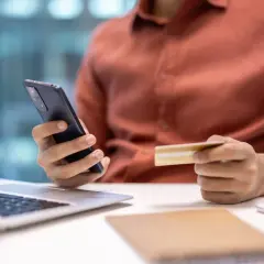 Mężczyzna trzyma telefon i kartę, szukając informacji, jak zrezygnować z Tidal.