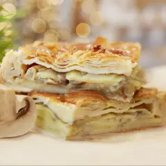 Chrupiące ciasto francuskie z kurczakiem i grzybami, podane z połówką pieczarki.