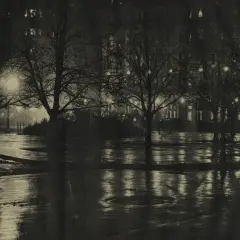 Nocny park, mokre alejki odbijające światła latarni i okien. Piktorializm w fotografii oddaje nastrój i atmosferę.