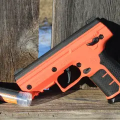 Pomarańczowy pistolet Byrna SD i pojemnik z pociskami, przykład legalnej broni do samoobrony.
