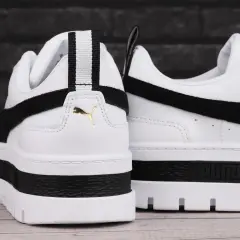 Białe buty sportowe Puma Mayze Leather z czarnymi akcentami i złotym logo. Gruba podeszwa dodaje im charakteru.