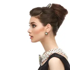 Elegante mujer con moño italiano, collar de perlas y pendientes llamativos.