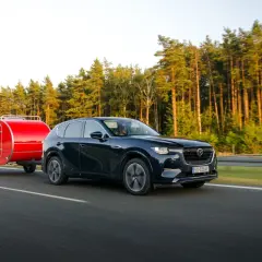 Ciemny SUV z czerwoną przyczepką typu teardrop jedzie po autostradzie. Zastanawiasz się, ile można jechać z przyczepką?