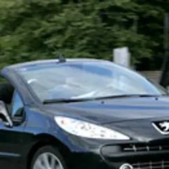 Czarny kabriolet Peugeot 207 CC z opuszczonym dachem jedzie po drodze.
