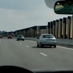 Panneau de signalisation au sol indiquant la vitesse minimale autoroute de 80 km/h. Plusieurs voitures circulent sur la voie rapide.