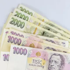 Kupka banknotów 1000 i 2000 koron czeskich, czyli waluta w Czechach, leży na białym tle.