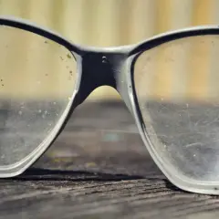 Brudne okulary ochronne leżą na drewnianej powierzchni. Czas na polerowanie okularów, by znów były przejrzyste.