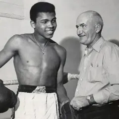 En ung Muhammad Ali ler mot sin tränare i ringen.