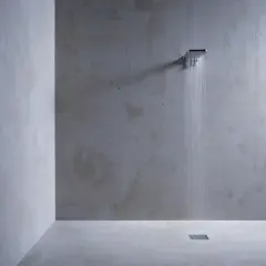 Douche moderne au design épuré, avec un mur et un sol en béton ciré. L'eau coule d'une douchette carrée, créant une ambiance zen.