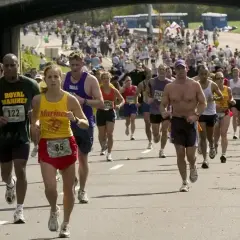 Uczestnicy biegną w maratonie, walcząc o jak najlepszy czas. Widać tłum biegaczy i kibiców.
