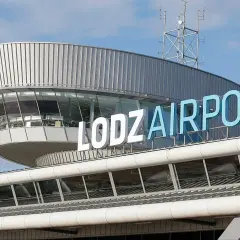 Budynek lotniska w Łodzi z napisem "ŁÓDŹ AIRPORT" na niebieskim niebie.
