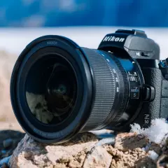 Nikon Z 50, jeden z popularnych bezlusterkowców, leży na kamieniach w zimowej scenerii.