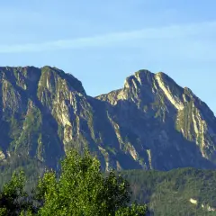 Majestatyczny Giewont, niczym śpiący rycerz, wznosi się na tle błękitnego nieba. Jego skaliste zbocza porośnięte zielenią tworzą imponujący krajobraz.