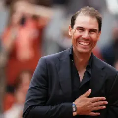 Uśmiechnięty Rafael Nadal, imię nadane temu słynnemu tenisisty, w czarnym garniturze i koszuli, z ręką na sercu.