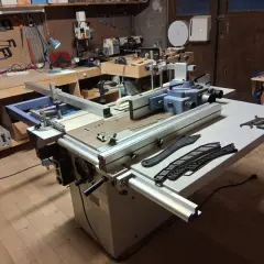 Un atelier de menuiserie avec une machine combinée Felder KF 500, des outils et des planches de bois.