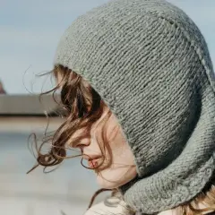 Una joven con un gorro tejido gris, que recuerda al balaclava origen, mira al horizonte.