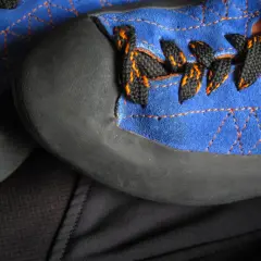 Zbliżenie na niebieskie buty wspinaczkowe z czarnymi sznurówkami i pomarańczowymi przeszyciami. Przygotowanie do podklejania butów wspinaczkowych.