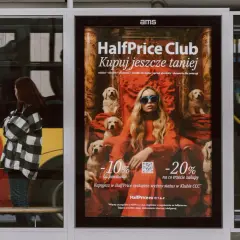 Plakat reklamuje HalfPrice Club, zachęcając do zakupów z rabatami. Aplikacja HalfPrice to szansa na niższe ceny.