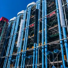 Centrum Pompidou w Paryżu z błękitnymi rurami i kolorowymi elementami architektonicznymi pod błękitnym niebem.