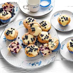 Pyszne muffiny z jagodami, udekorowane kremem i świeżymi owocami, kuszą swoim wyglądem i zapachem.