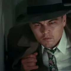Leonardo DiCaprio, dans la distribution de Shutter Island, porte un chapeau et un trench-coat, l'air intense et méfiant.