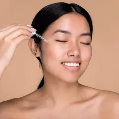 Donna applica acido ialuronico sul viso con un contagocce per una pelle idratata e luminosa.