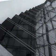 Ciemne schody z polerowanego konglomeratu odbijają architektoniczne detale, tworząc geometryczne wzory.