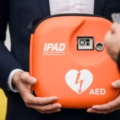 Pomarańczowy AED w etui, z sercem i błyskawicą. Zastanawiasz się, ile kosztuje AED?