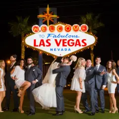 Ślub w Las Vegas jest ważny w Polsce? Para młoda całuje się pod neonem "Welcome to Fabulous Las Vegas", otoczona przez świadków.