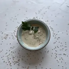 Cremige Sauce in einer Schale, garniert mit Petersilie und Sesam. Was ist Tahin? Eine köstliche Sesampaste, die hier als Dip serviert wird.