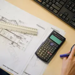 Rysunki techniczne, kalkulator i linijka na biurku. Przygotowanie kosztorysu budowlanego.