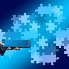 Biznesmen w garniturze trzyma tablet, a za nim układanka z puzzli symbolizuje wiedzę i rozwiązanie.