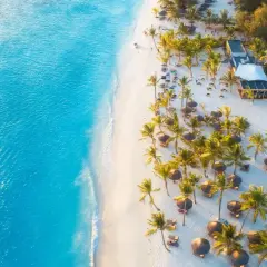 Rajska plaża na Zanzibarze w grudniu. Turkusowa woda, biały piasek, palmy i leżaki. Idealna pogoda na wakacje.