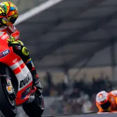 Valentino Rossi en su Ducati, número 46, inclinado en una curva. Otro piloto yace en el suelo.