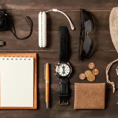 Zestaw EDC: aparat, pendrive, notes, długopis, zegarek, okulary, monety, portfel, słuchawki i woreczek.